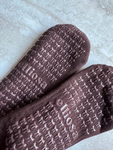Close-up of a customer's brown Dual-Direction Grip Basics socks, highlighting the bow-shaped grips on the bottom.
