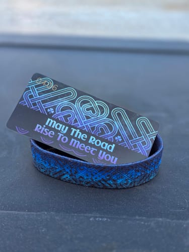 Customer's blue woven May The Road Rise To Meet You Bracelet shown with its collector card.