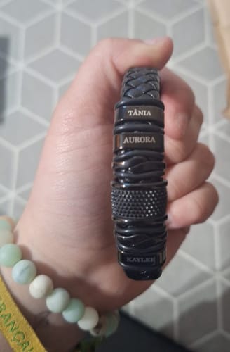 Customer's hand holding the personalized black bracelet, showing several engraved names on the beads.