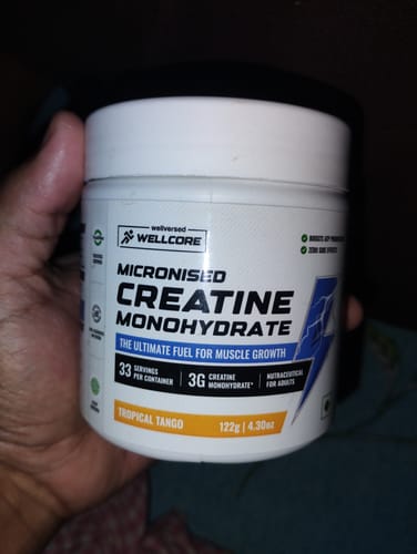 Customer holding a white tub of Wellcore Pure Micronised Creatine Monohydrate in the Tropical Tango flavor.