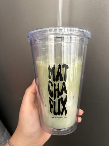 Una clienta sostiene el Vaso Oficial de Matchaflix, transparente y con una bebida de matcha en su interior.