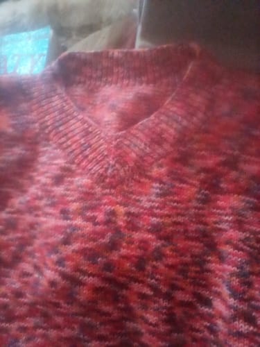 Close-up of a reviewer's finished Bright Side Jumper, showing the colourful v-neck collar and soft knitted yarn.