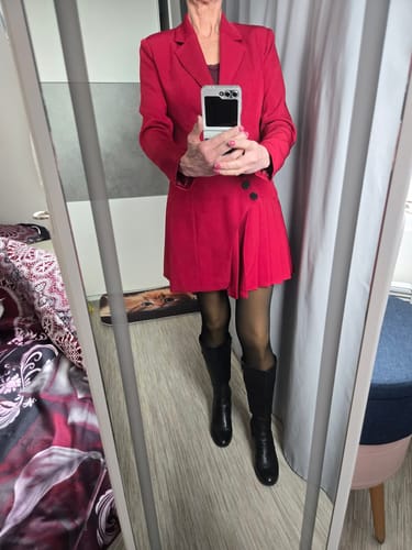 Kunde som har på seg den røde jakkekjolen, stylet med svarte støvler.