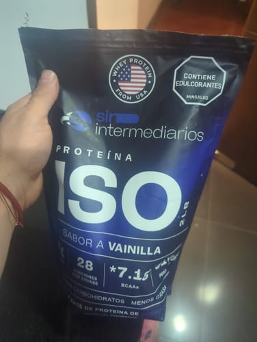 Cliente sosteniendo el empaque negro y azul de Proteína ISO sabor a vainilla.