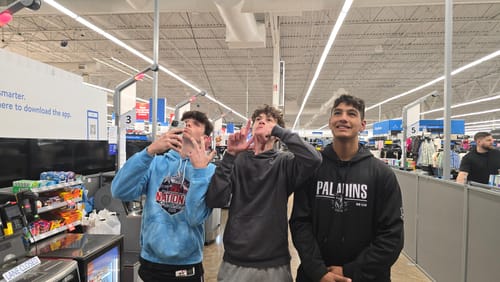 Customers, three young people, posing together inside a retail store.
