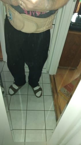 Vásárló egy tükör előtt, a bézs Dekompressziós Deréktámasztó Övet viselve.