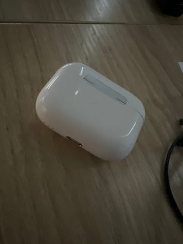 Customer's white charging case for the LOT Earbuds resting on a wooden surface.
