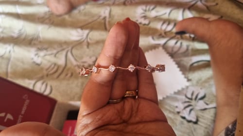 Customer's hand holding the Rose Gold Glimmering Statement Bangle, showing the delicate zircon-studded wave design.