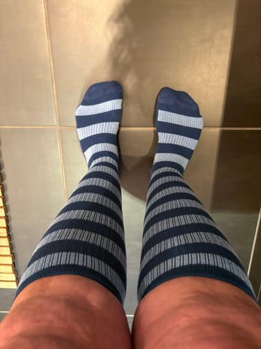 Anmelder, der har blå og lyseblå stribede støttestrømper på, set oppefra.