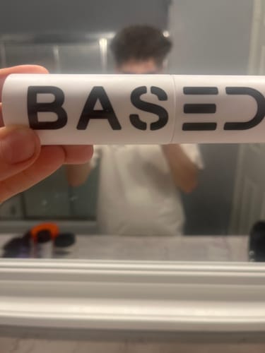 Customer holding the white 'Based' Texture Powder container in front of a bathroom mirror.