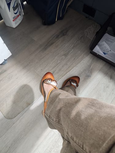 Customer wearing the brown leather Retro Leather Grace Adjustable Belt Pumps while seated on a light floor.