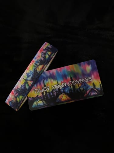 Customer's Trust Your Compass Bracelet and matching card. Both feature a colorful aurora borealis over a peaceful campsite.