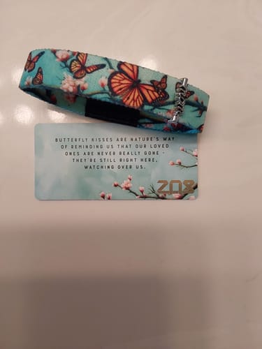 Customer's Mom Text Charm on a blue bracelet with an orange butterfly pattern, shown next to a collectible card.