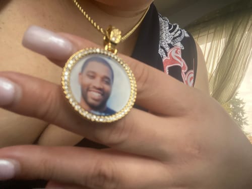 Close-up of a reviewer holding the gold-colored Diamond Studded Photo Necklace, showing a loved one's picture inside the pendant.