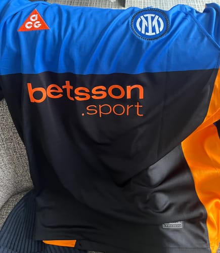 Un cliente mostra un primo piano della Maglia Inter Home 2025/26, evidenziando lo stemma e lo sponsor arancione.