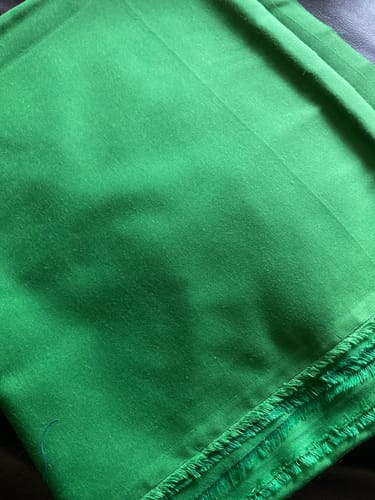 Customer showing a folded piece of bright green Plain Polycotton Fabric.