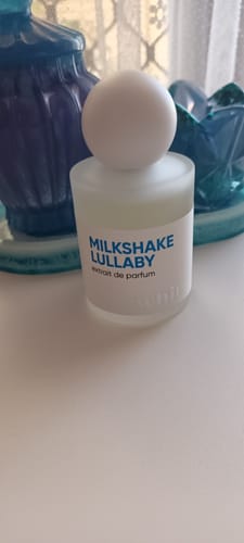 Customer's bottle of Milkshake Lullaby perfume in its frosted glass bottle with a white spherical cap, resting on a white surface.