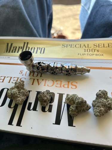 Reviewer's four dense Headband flower nugs laid out next to a silver pipe.