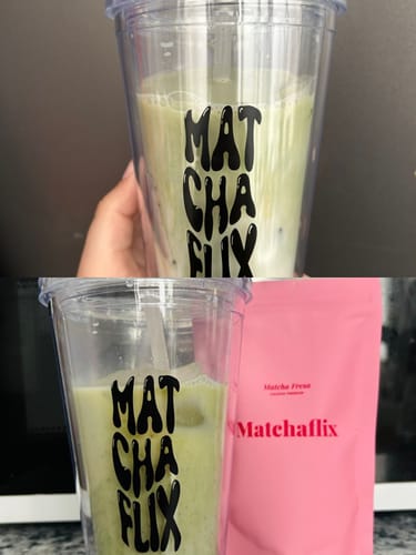 Un cliente muestra el Té Matcha Premium Fresa preparado en un vaso junto a su empaque rosa.