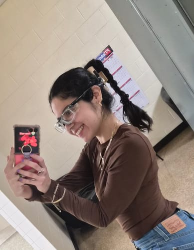 Reviewer smiling with their dark wavy hair in a high braided ponytail held by a cloud clip.