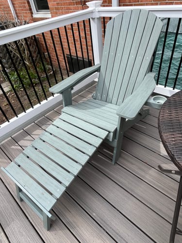 Customer's gray folding Adirondack chair on a deck with its built-in footrest extended.