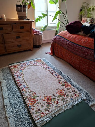 Customer's beautiful Barakah Padded Prayer Mat laid out on a carpeted floor in a bedroom.