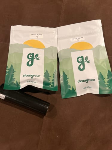 Customer's cleangreen brand packaging, with two white pouches and a black tube on a brown surface.