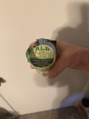 Customer holding a stack of ALP Spearmint Nicotine Pouches containers.