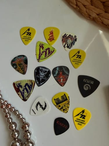 Customer image displaying a collection of assorted guitar picks on a white surface.