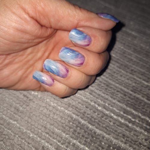 Kundenhand, die die aufgetragenen 'Pastel Waves' UV Gel-Folien mit einem sanften, wellenförmigen Muster in Pastellfarben zeigt.