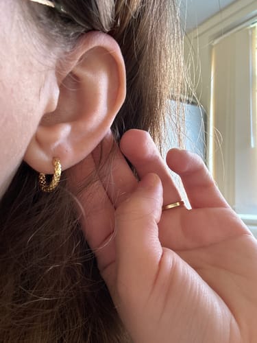 Close-up of a reviewer wearing a small, textured JOVIE Hoops earring.