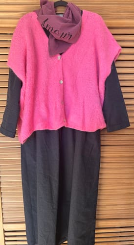 Photo d'un client montrant la robe Edonie ardoise chiné sur un cintre, portée avec un gilet rose et un foulard.