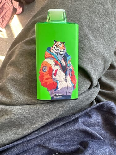 Kundenfoto eines leuchtend grünen RANDM TORNADO 35000 mit Tiger-Grafik, der auf dem Schoß liegt.