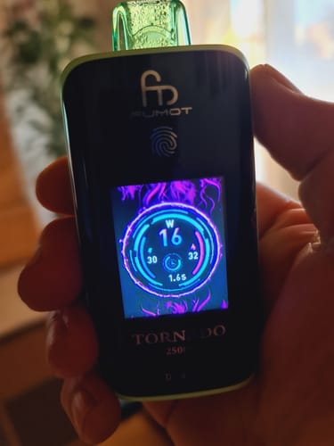 Ein Kunde hält den schwarzen RANDM TORNADO 25000 in der Hand, dessen beleuchtetes TFT-Display aktiv ist.