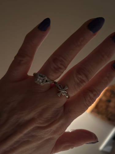A reviewer's hand wearing the silver Mobius Cross Ring next to another ornate ring.