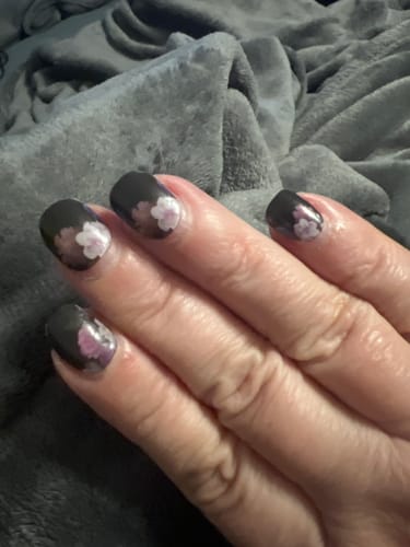 Nahaufnahme der Nägel einer Kundin mit den leicht herausgewachsenen UV-Gel-Nagelfolien 'Midnight Foliage'.