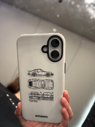 Customer holding their phone with the white Beat The Traffic case, showing the black car blueprint design.