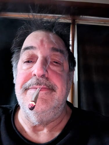 Close-up of a reviewer smoking a lit White Runtz Pre-Roll.