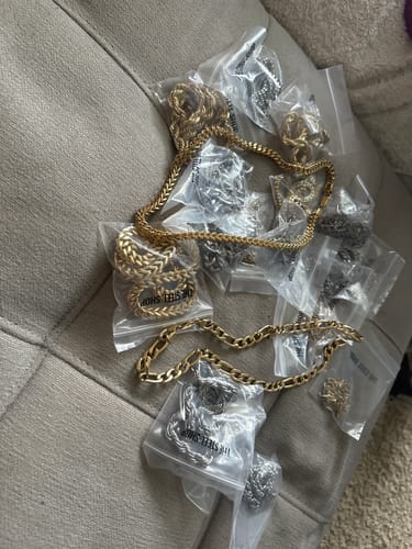 Customer's haul from the Mystery Chains Box, showing a large pile of gold and silver-tone chains on a couch, some still packaged.