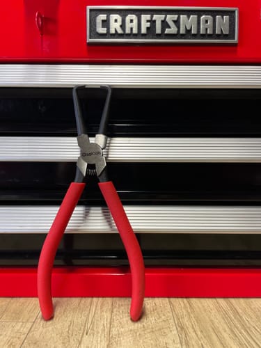 Customer's Electrical Disconnect Pliers with red handles standing upright in front of a red toolbox.