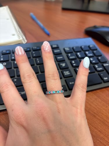 Customer wearing the Eterna Birthstone Ring with pink and light blue stones on their finger.