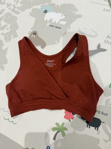 Customer's rustic Chloe Dream Love Organic Bra laid flat on a colorful children's playmat.
