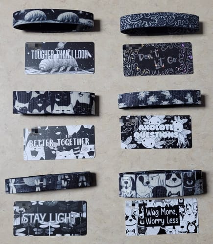 Reviewer's six black and white Mystery Club+ bracelets and cards, featuring animal and insect designs.
