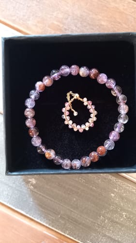 Client montrant le bel ensemble du Bracelet Auralite 23 et de la bague assortie dans une boîte noire.
