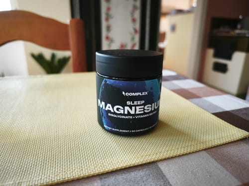 Reviewer's tub of a Complex supplement, specifically the Sleep Magnesium product, on a dining table.