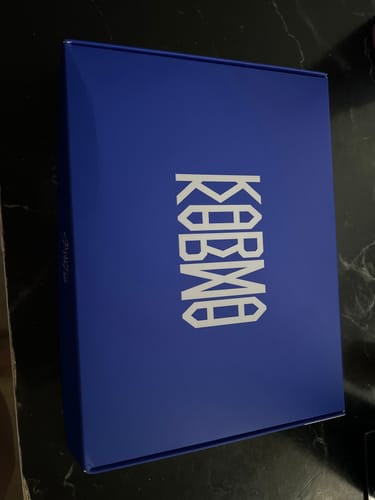 Reviewer shows the blue 'Karma' K-pop album box they received from their random album order.