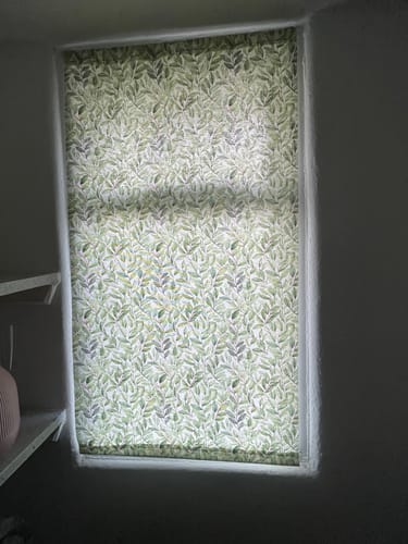 Reviewer shows a leaf-patterned curtain hung in a small window using the Hemline Curtain Wire.