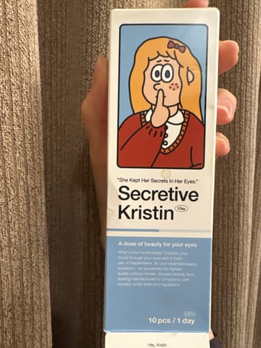 レビュアーが手に持つ「Secretive Kristin 1Day - クリームブラウン」の箱。