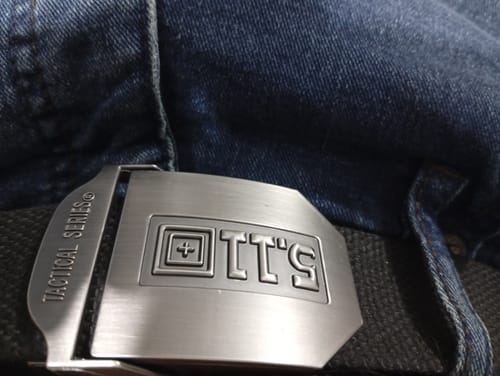 Close-up of a reviewer's 5.11 Tactical Belt, highlighting the detailed stainless steel buckle while being worn.