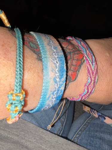 Close-up of a reviewer's Remember Who You Are Bracelet on their wrist, stacked with other woven bracelets.